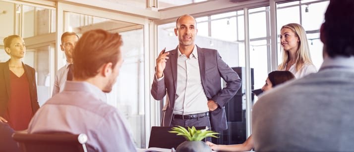 Senior man talking to employees in office meeting. Marketing team discussing new ideas with manager during a conference. Senior leadership training future businessmen and businesswomen.