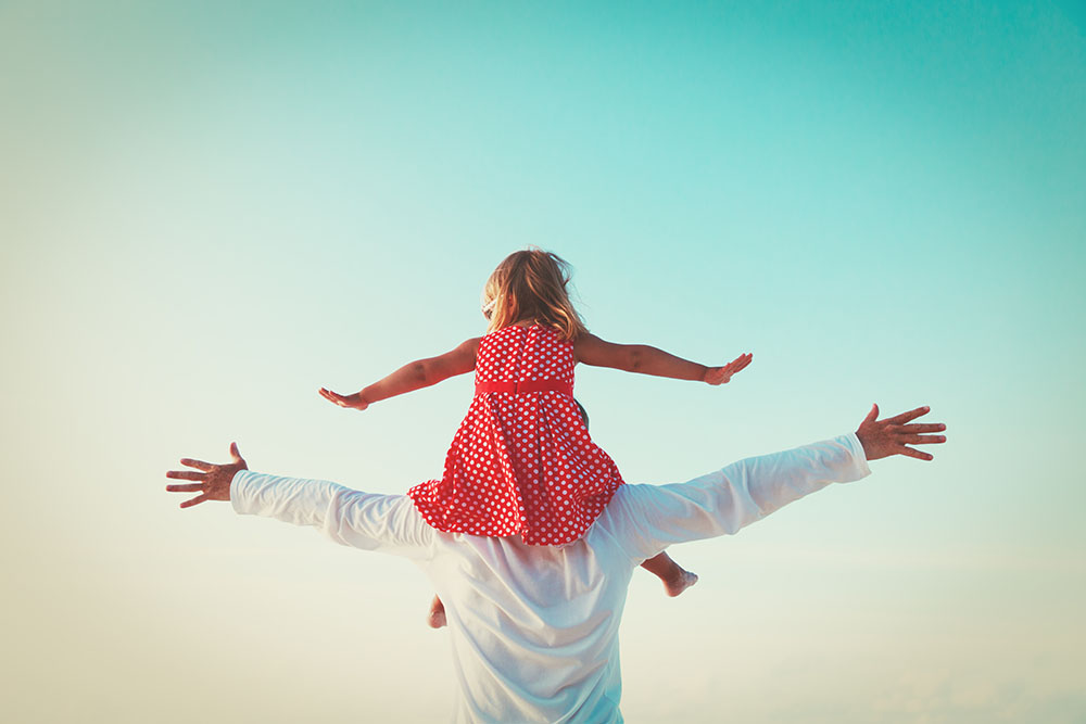 A father places his daughter on his shoulders.