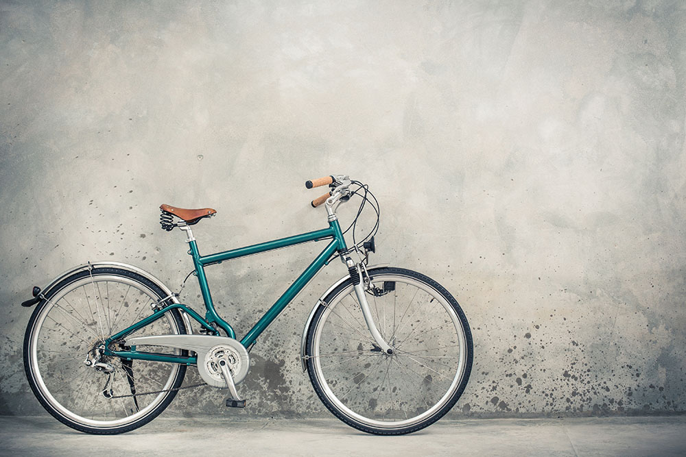 Retro bicycle with aged brown leather saddle from circa 90s front concrete wall background. Vintage old style filtered photo